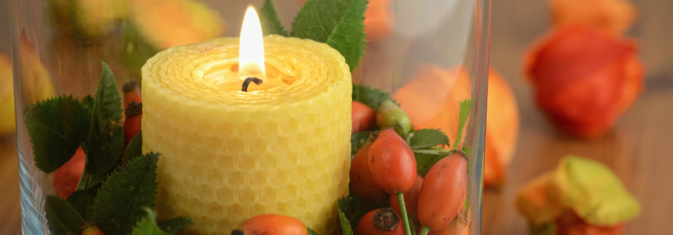 Candle burning with rose hips around it