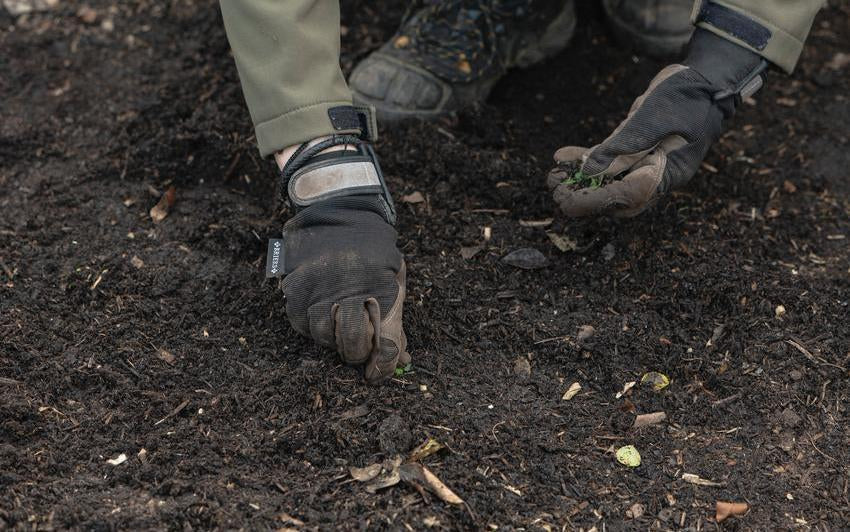 Person clearing away leaves and weeds from soil